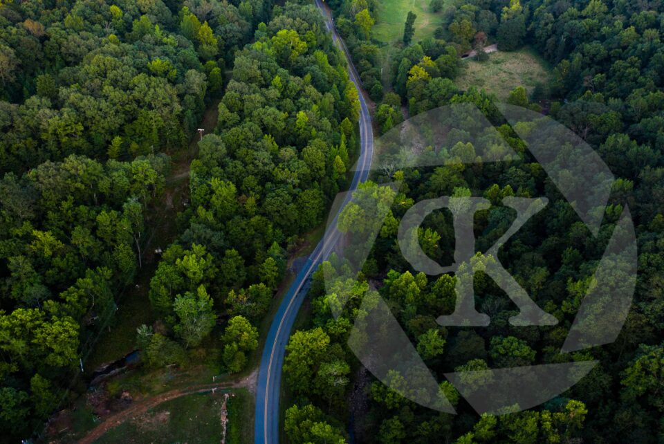 Aerial Shot of a backroad surrounded by trees and woods