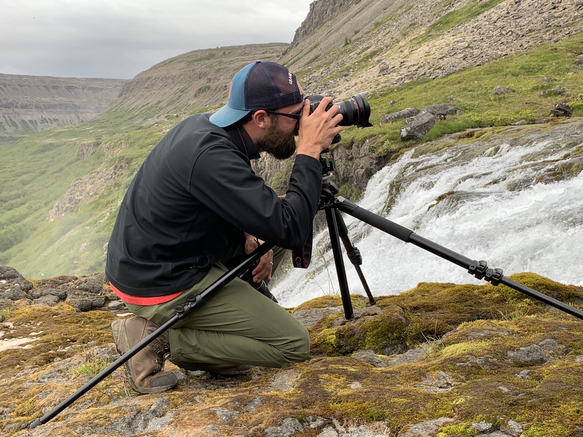 Photo of Paul Knightly kneeling and taking a photograph of the landscape